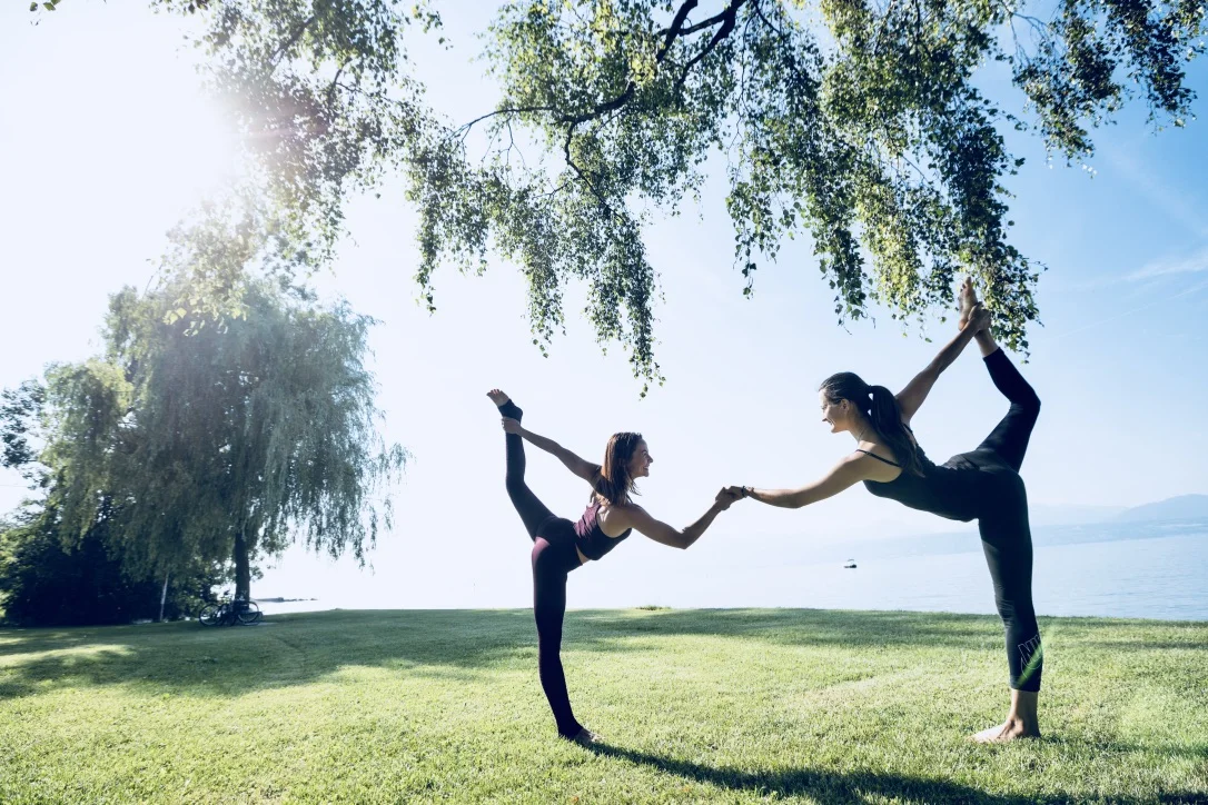 Partner yoga practice beside Lake Geneva