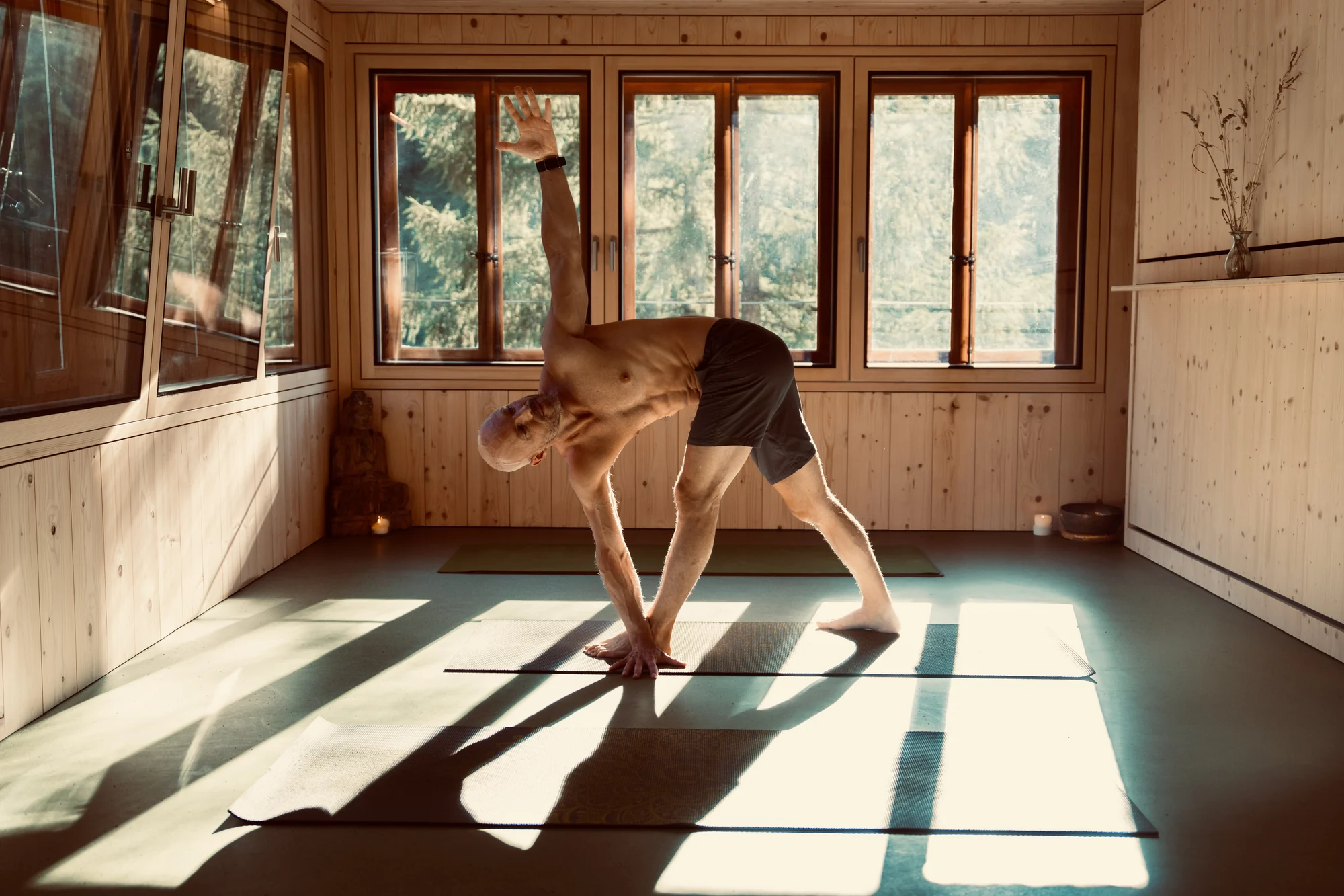 Felix tient le triangle en torsion, jambes tendues, une main près du pied avant et le bras opposé levé tandis que le buste tourne.