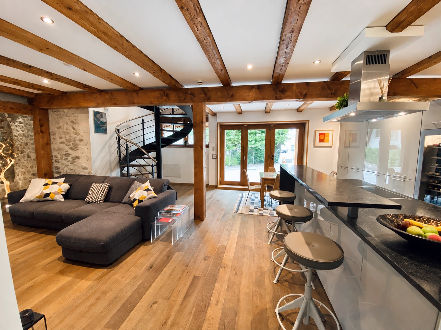 A warm home interior with timber beams, a stone wall and a comfortable sofa