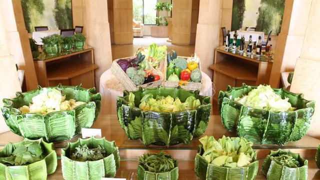 Un buffet présente des bols verts de salade et de légumes, ainsi que des paniers de produits frais.