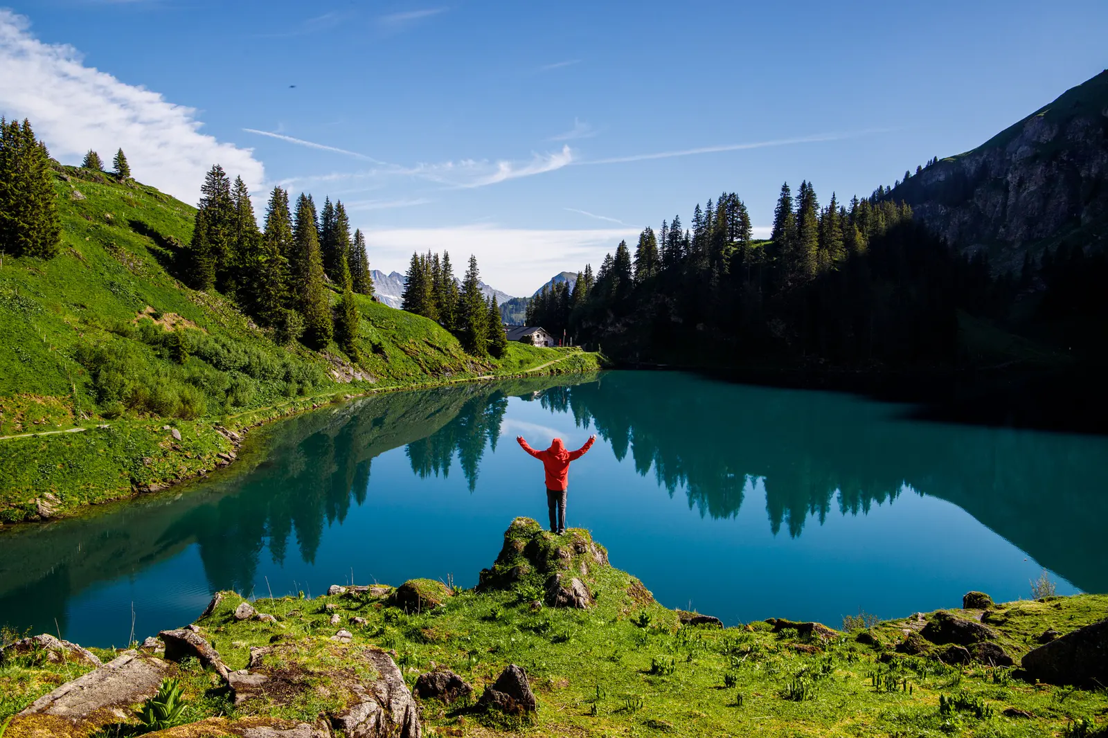 A UNITY retreat participant standing with open arms above Lac Lioson in the Swiss Alps