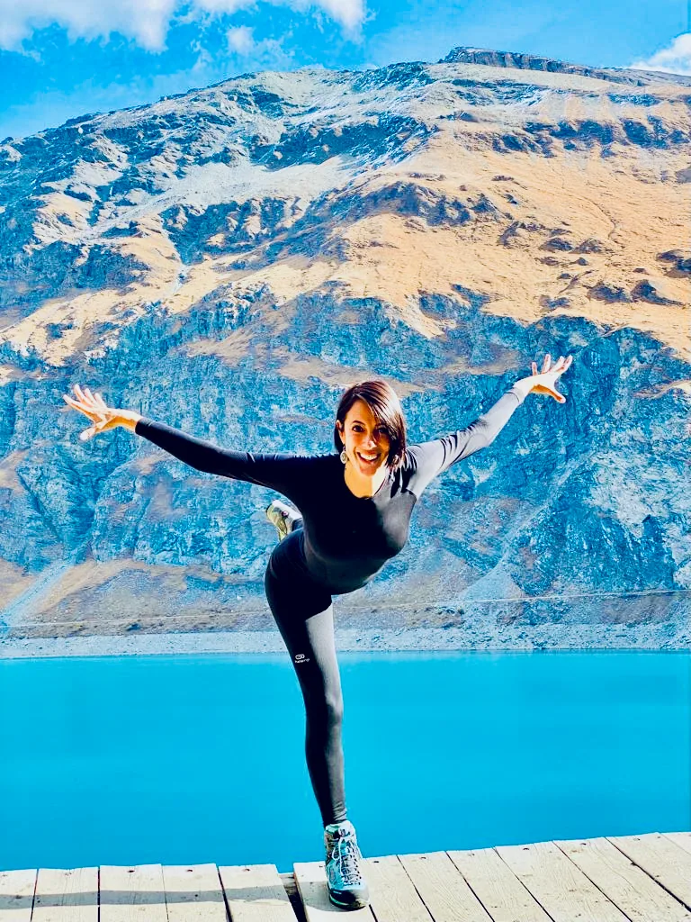 Alexia balancing in a yoga pose beside a mountain lake